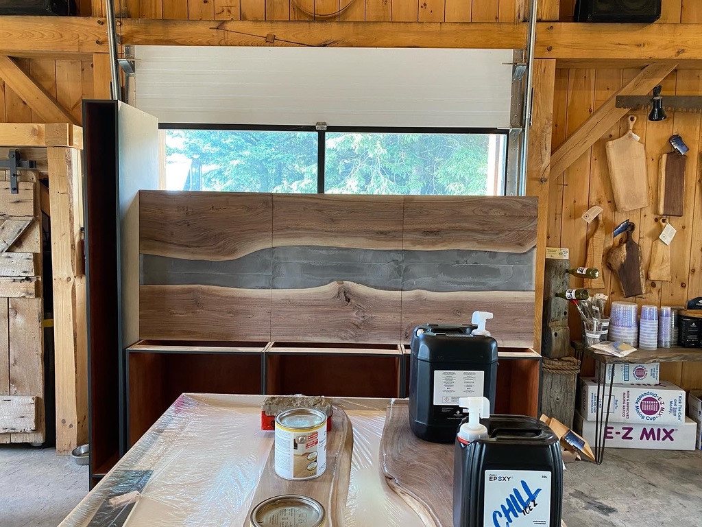 Walnut wet-bar cabinet panels during workshop assembly, with the live-edge epoxy band