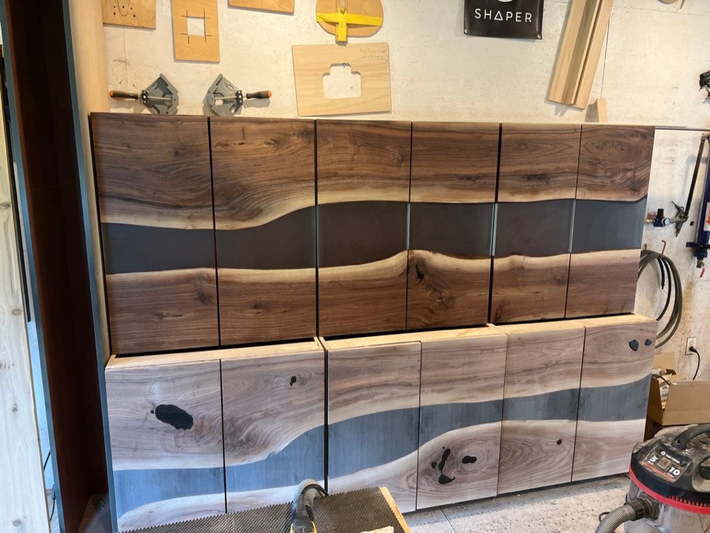 Walnut and epoxy wet-bar cabinet fronts fitted together in the workshop